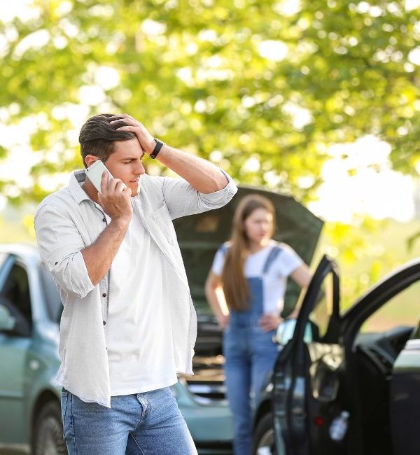 Man on phone and woman standing in front of a car accident