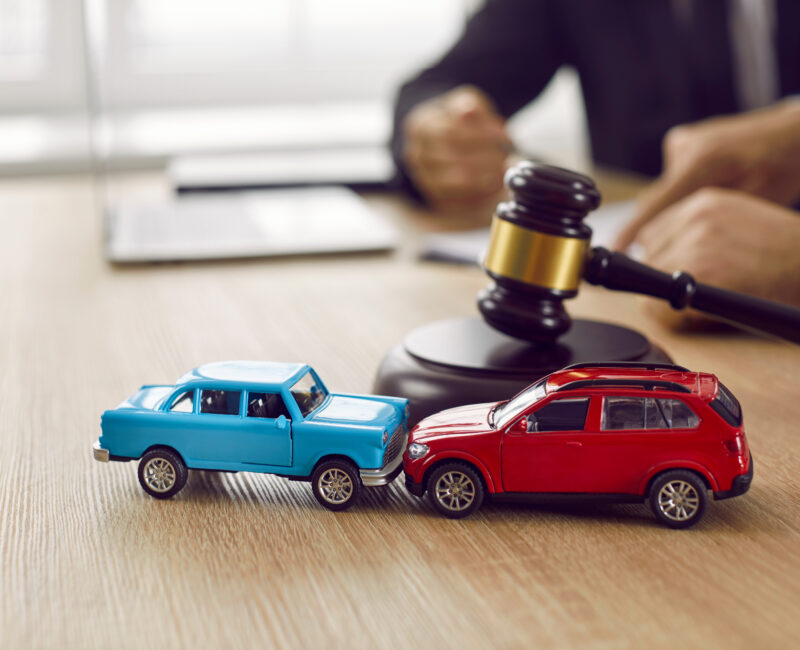 Two crashed toy automobiles on lawyer's table illustrating car accident