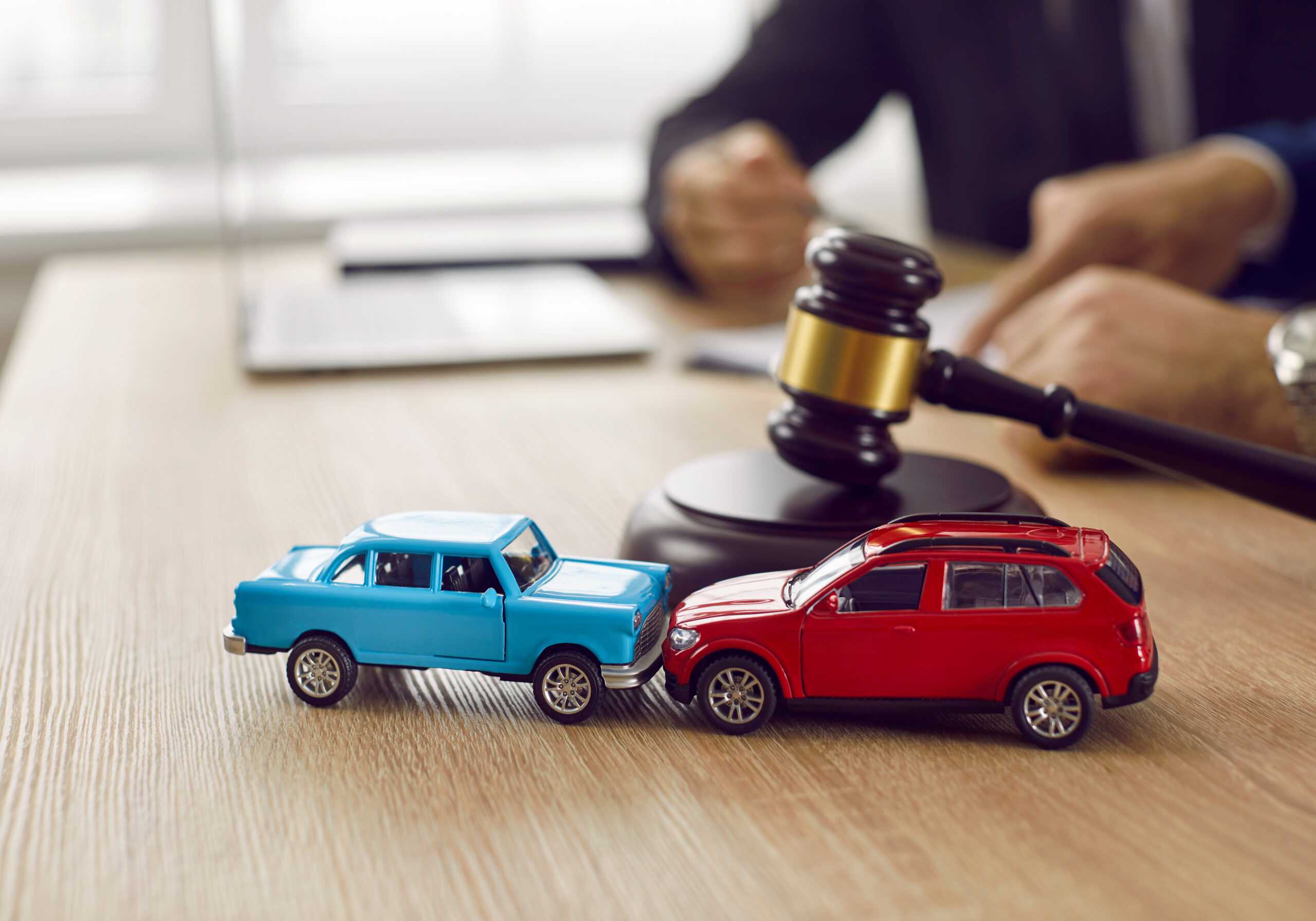 Two crashed toy automobiles on lawyer's table illustrating car accident