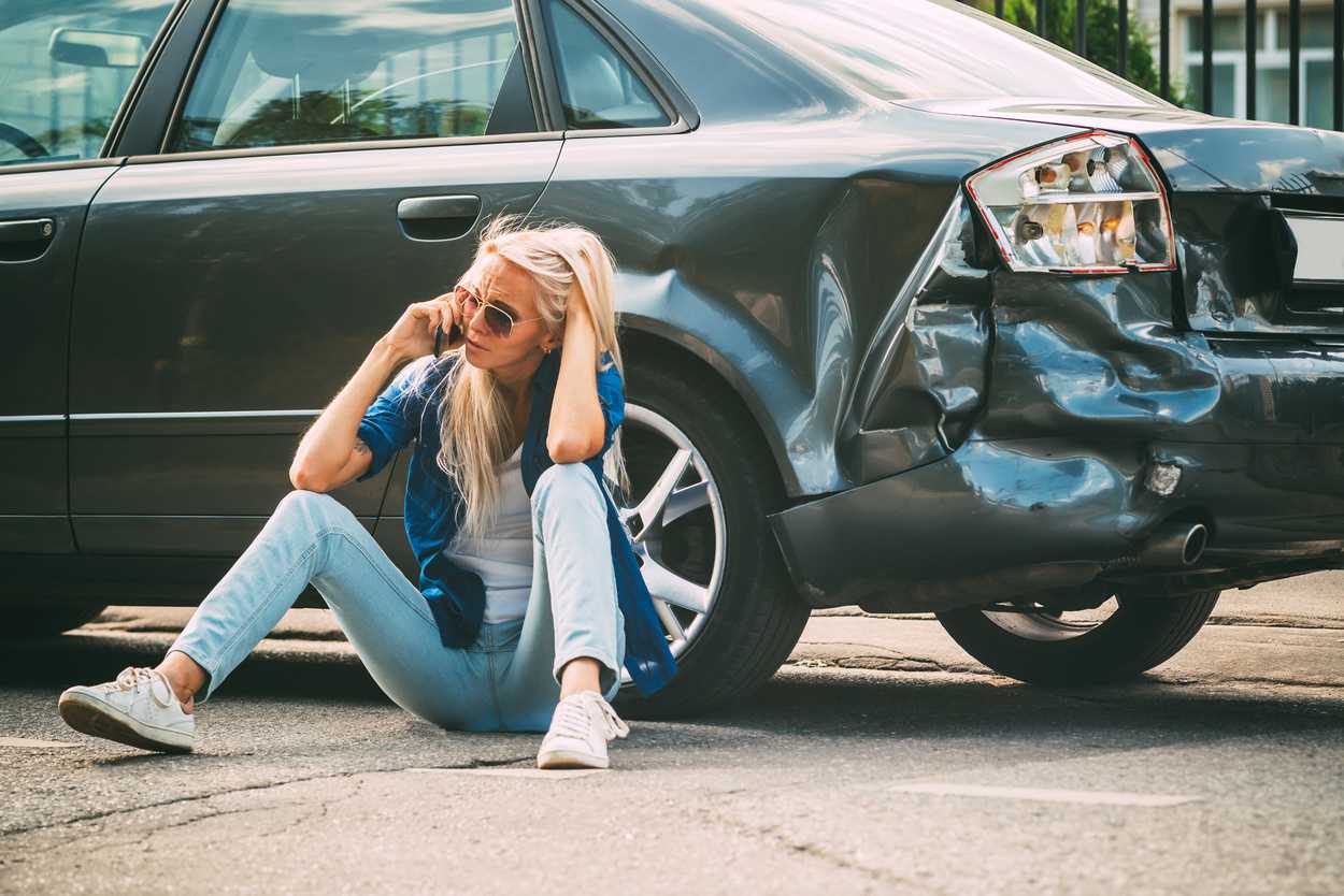 girl sits on the road, near the car which ran into accident